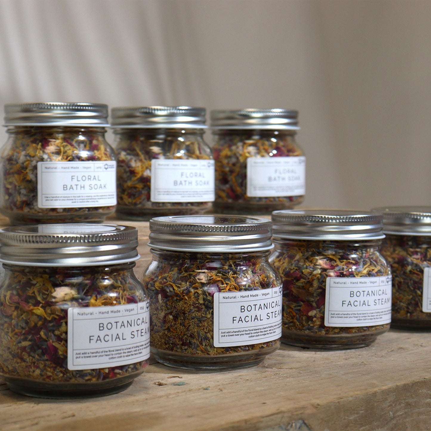 Jars of botanical facial steams on a wooden surface with a neutral background
