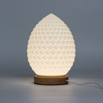 Close-up of lamp’s textured honeycomb pattern and soft diffused light, showing elegant teardrop shape and wooden base detail