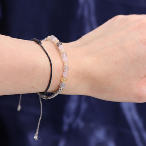 Close-up of a wrist wearing two beaded bracelets against a dark background