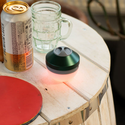Mint Rock Mini Bluetooth Speaker in cool mint tone with textured rock-inspired metal-style body, compact size shown next to phone for scale, playing music with subtle LED glow