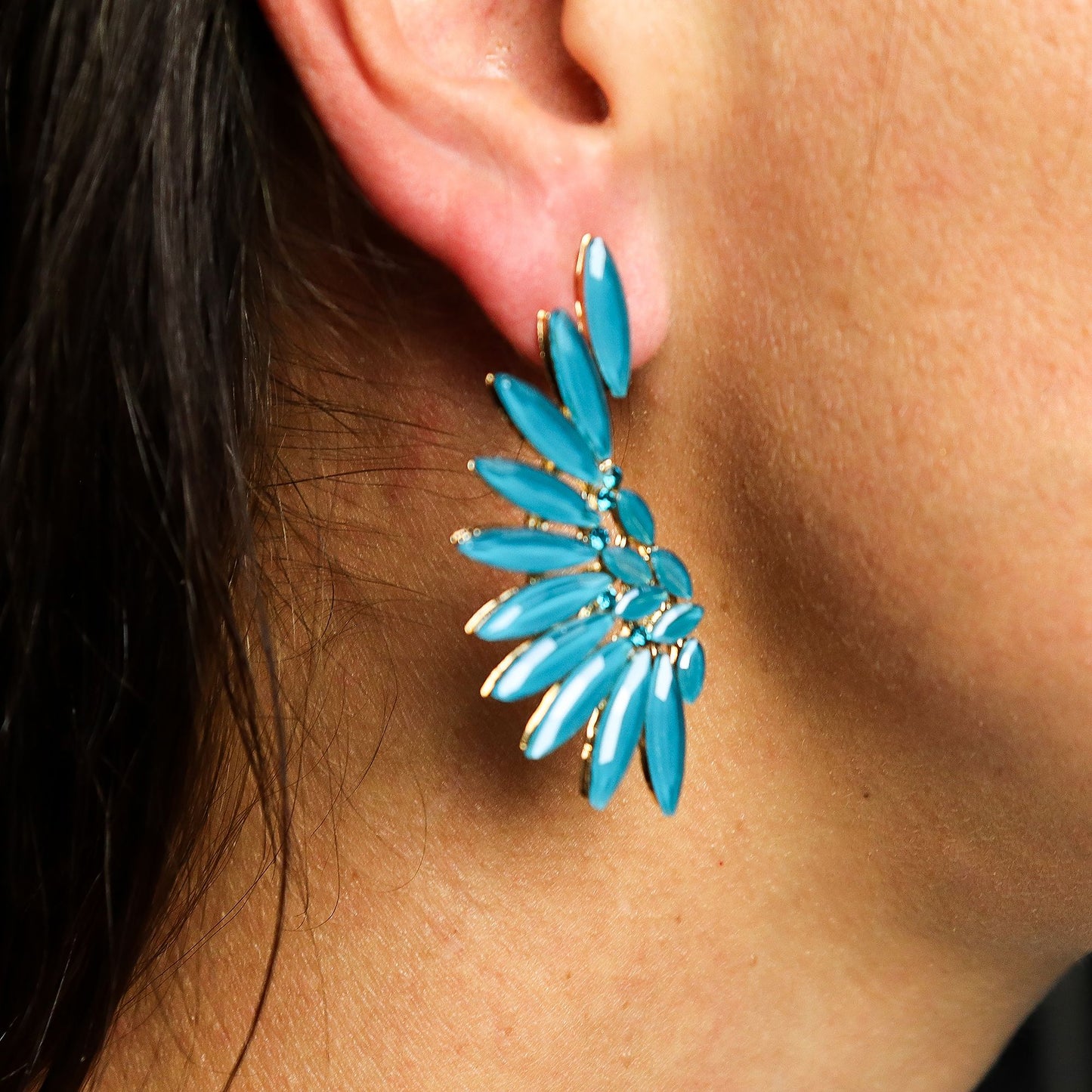 Teal green angel wing earrings with translucent vintage glass and silver stainless steel, hanging against forest backdrop with soft sunlight