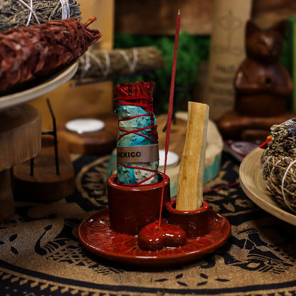 Glossy red ceramic mandala smudge holder with heart-shaped incense dish, Palo Santo stick burning, sage bundle on altar setting