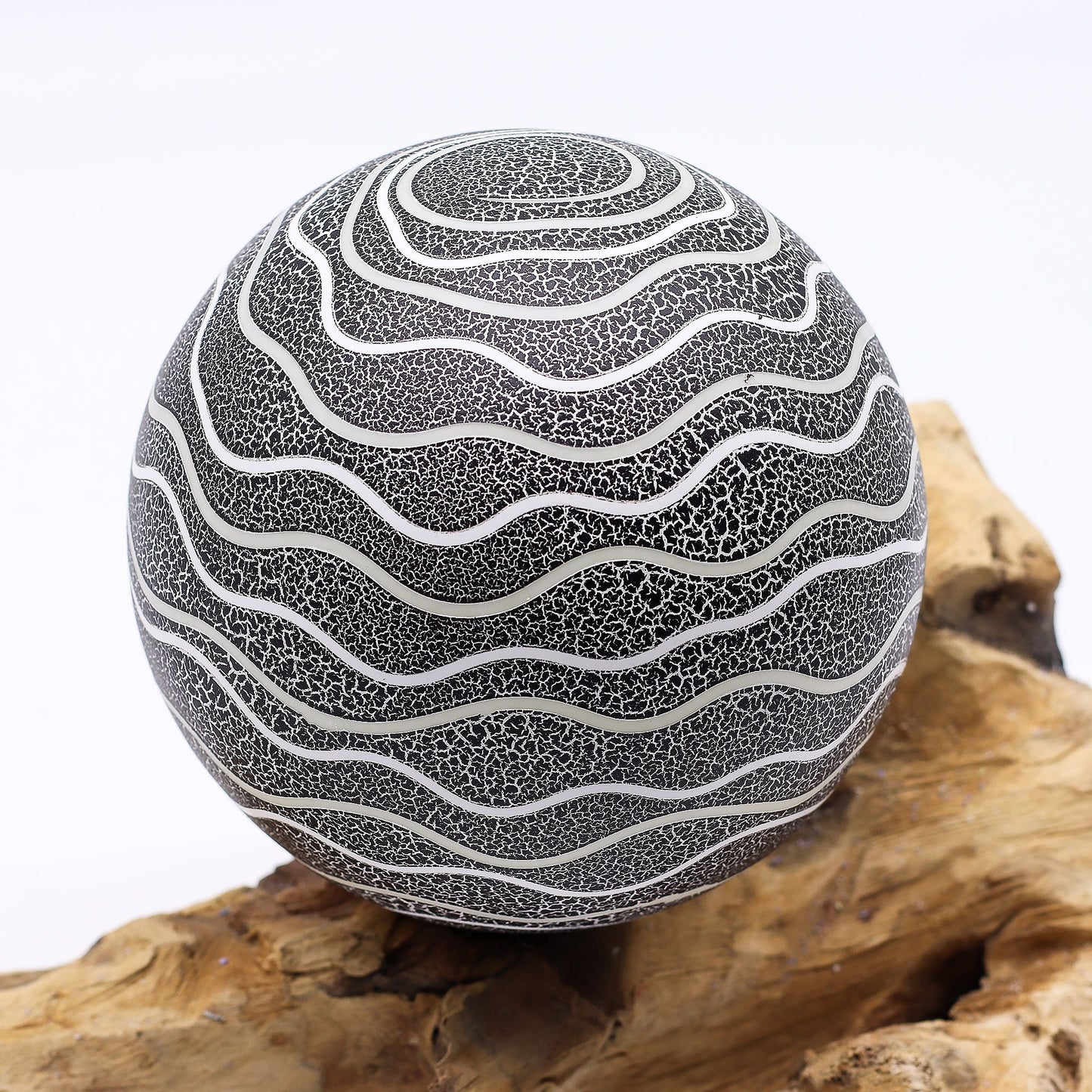 Grey Luna textured sphere glowing softly atop twisted driftwood base