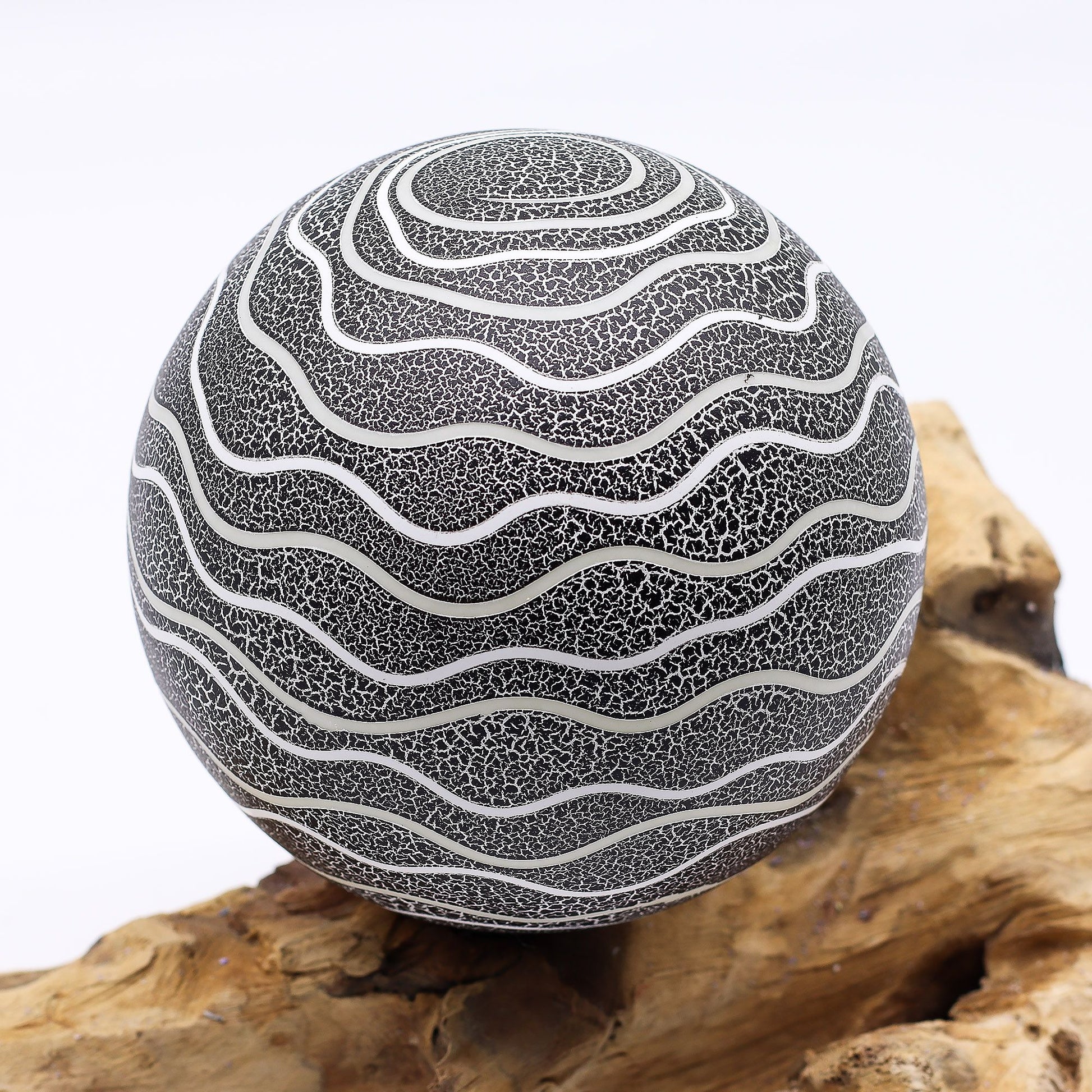 Grey Luna textured sphere glowing softly atop twisted driftwood base