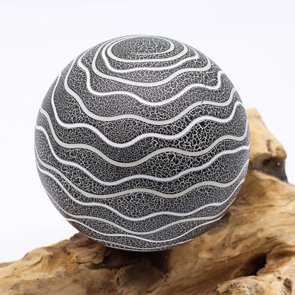 Grey Luna textured sphere glowing softly atop twisted driftwood base
