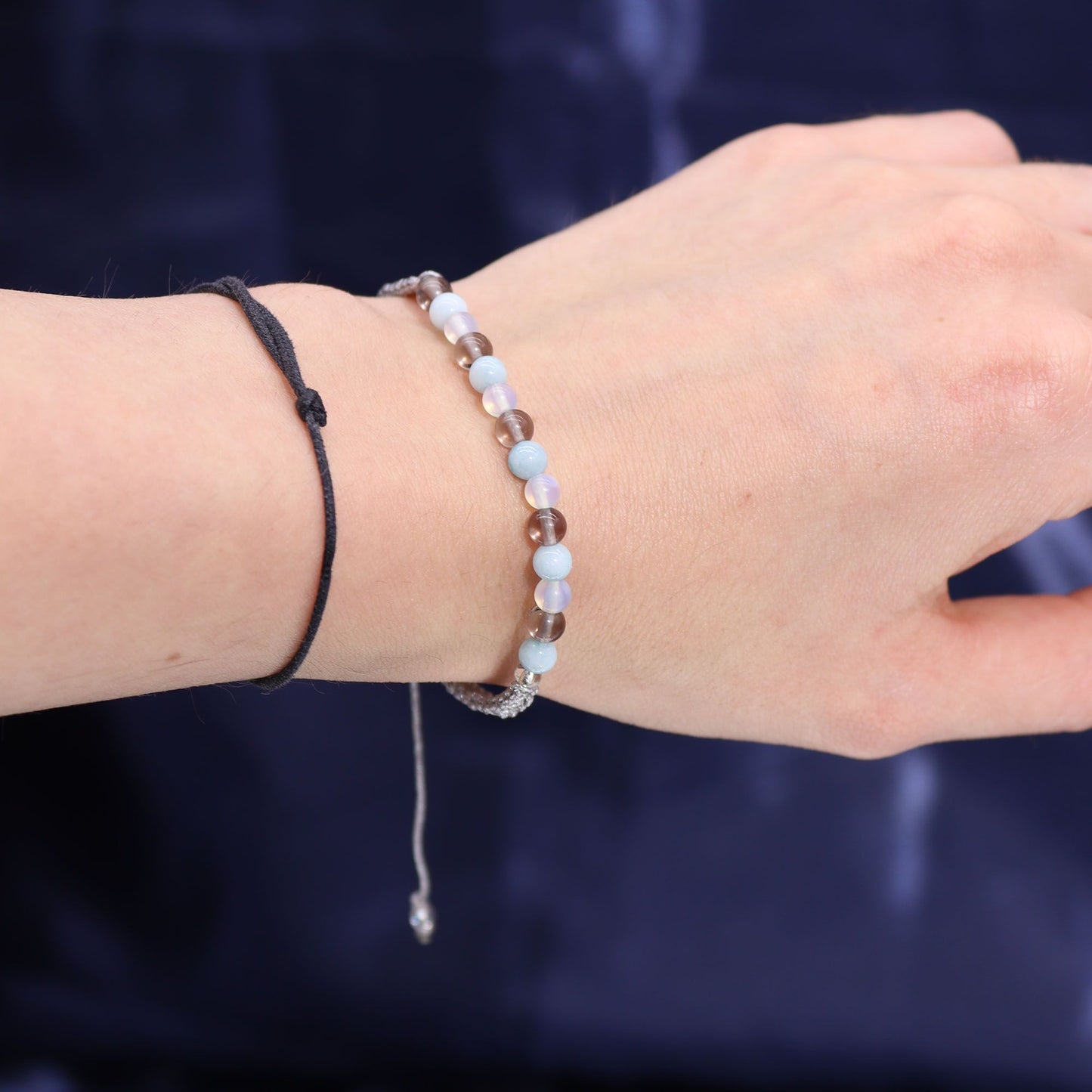 Close-up of a wrist wearing two bracelets against a dark background