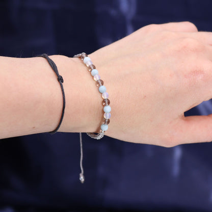 Close-up of a wrist wearing two bracelets against a dark background