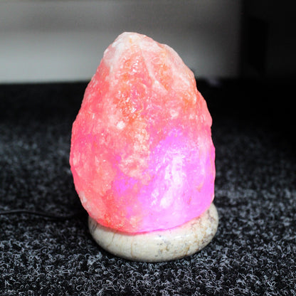 11.5cm natural pink Himalayan salt lamp glowing in multicolour LED mode on wooden base, USB cable visible
