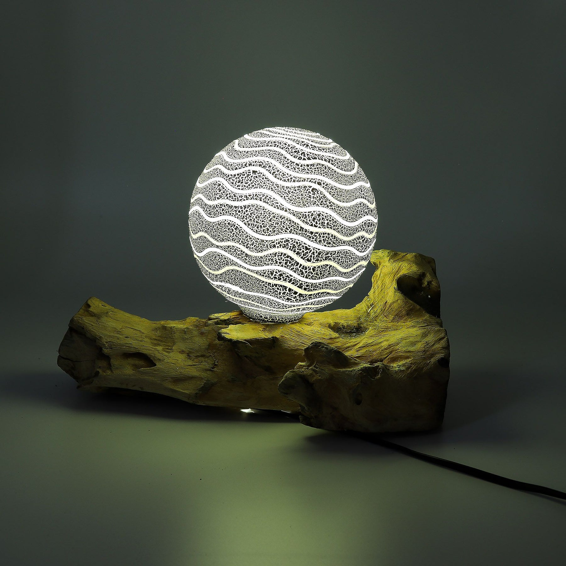 Grey Luna textured sphere glowing softly atop twisted driftwood base