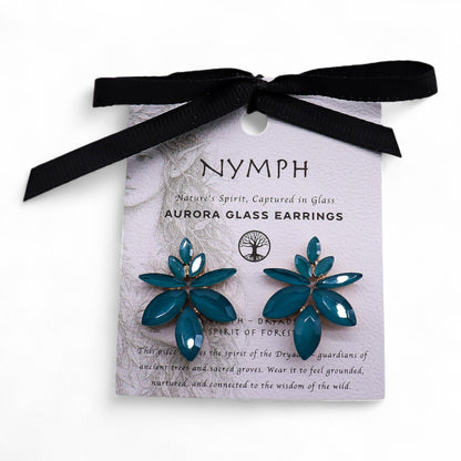 Teal green vintage glass flower earrings glowing like fresh spring leaves, styled on white linen with moss and tiny forest flowers