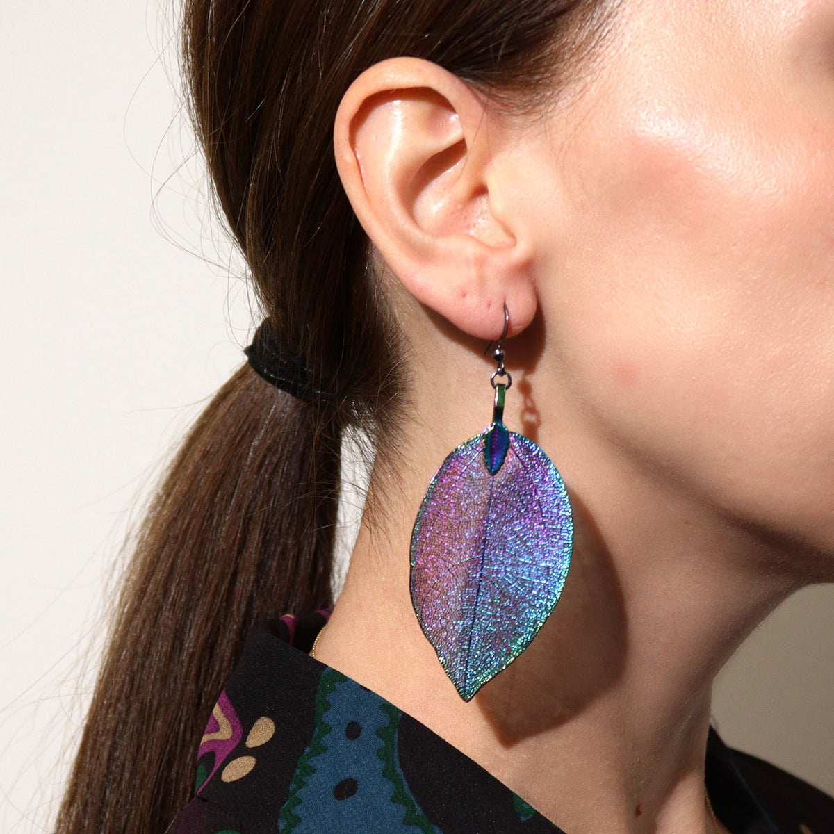 Close-up of a person wearing colorful leaf-shaped earrings