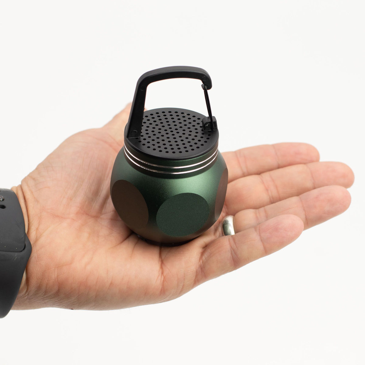 Hand holding a Camping Hook Green Mini Speaker with a carabiner 