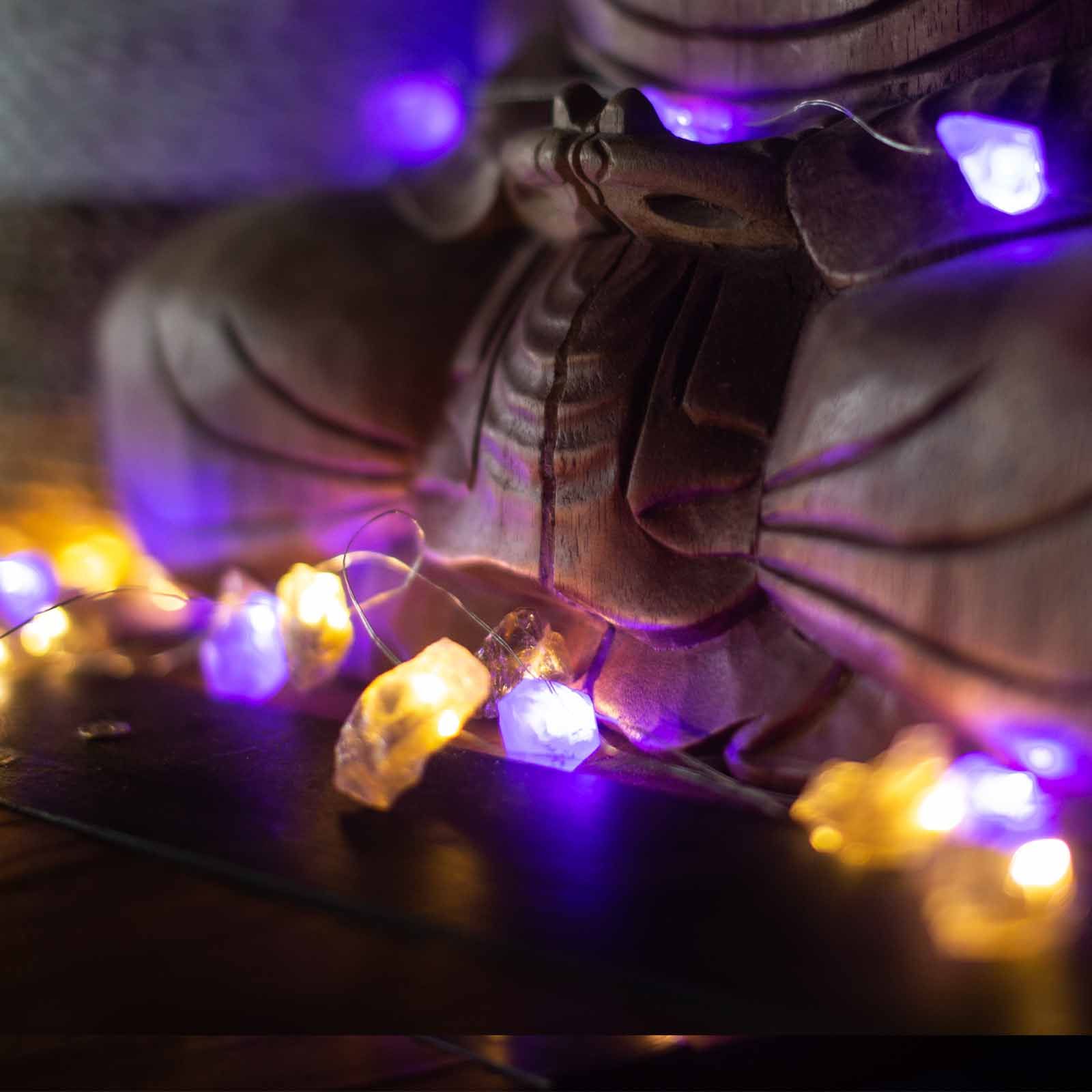 Mixed gemstone fairy lights glowing in glass bowl with amethyst, rose quartz, jade and clear quartz crystals sparkling on boho bedroom shelf