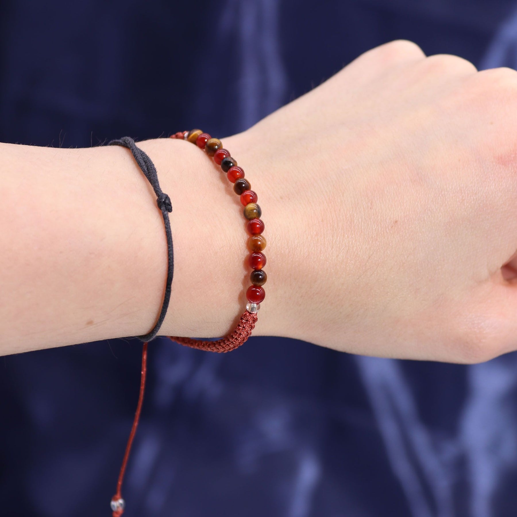 Close-up of a wrist wearing two bracelets against a dark background